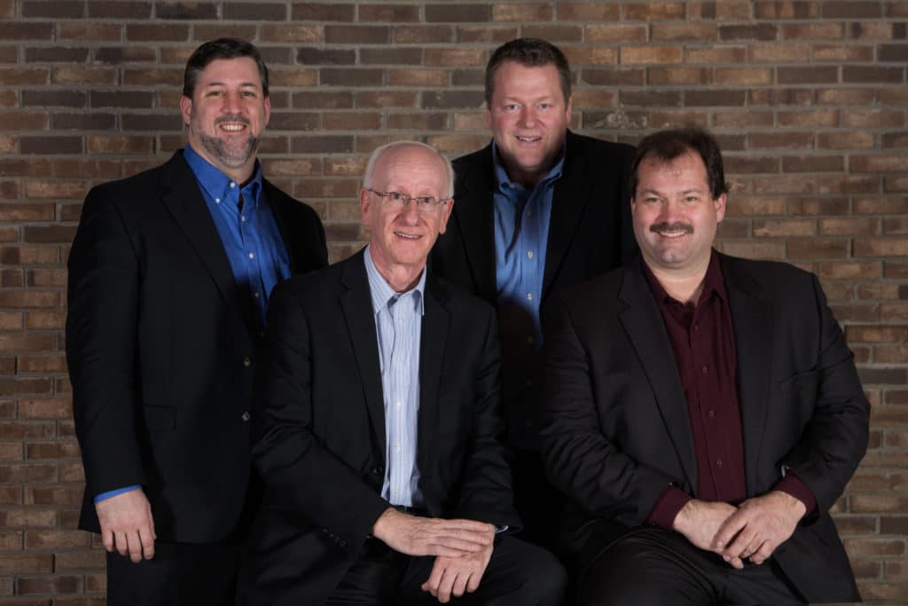 Stronghold Quartet — four men in business attire posed against a brick wall